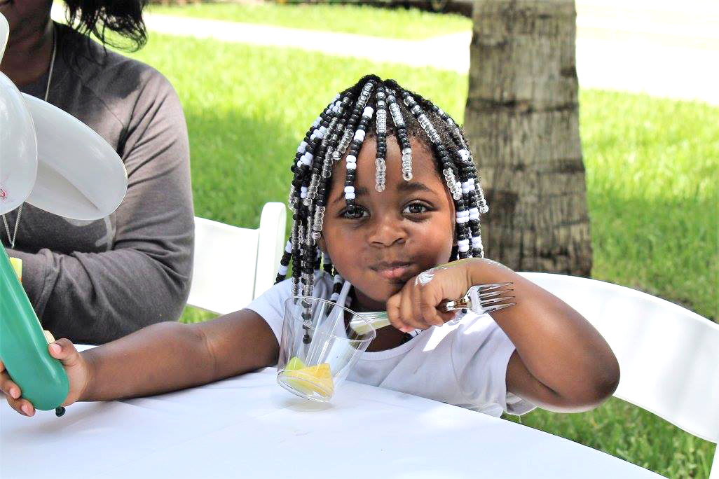 small female child eating fruit sitting at table