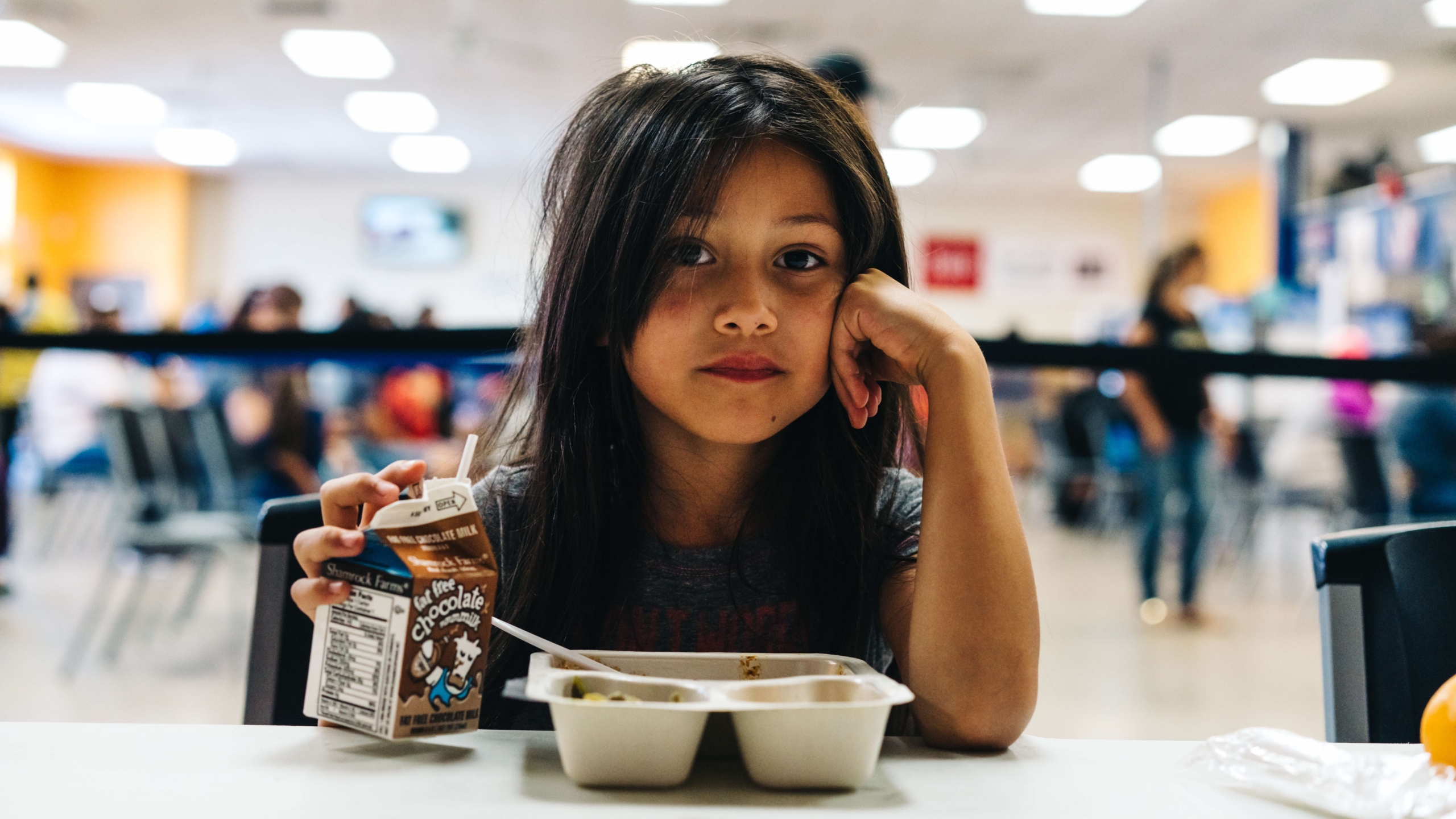 young female child sitting at lunch table drinking milk