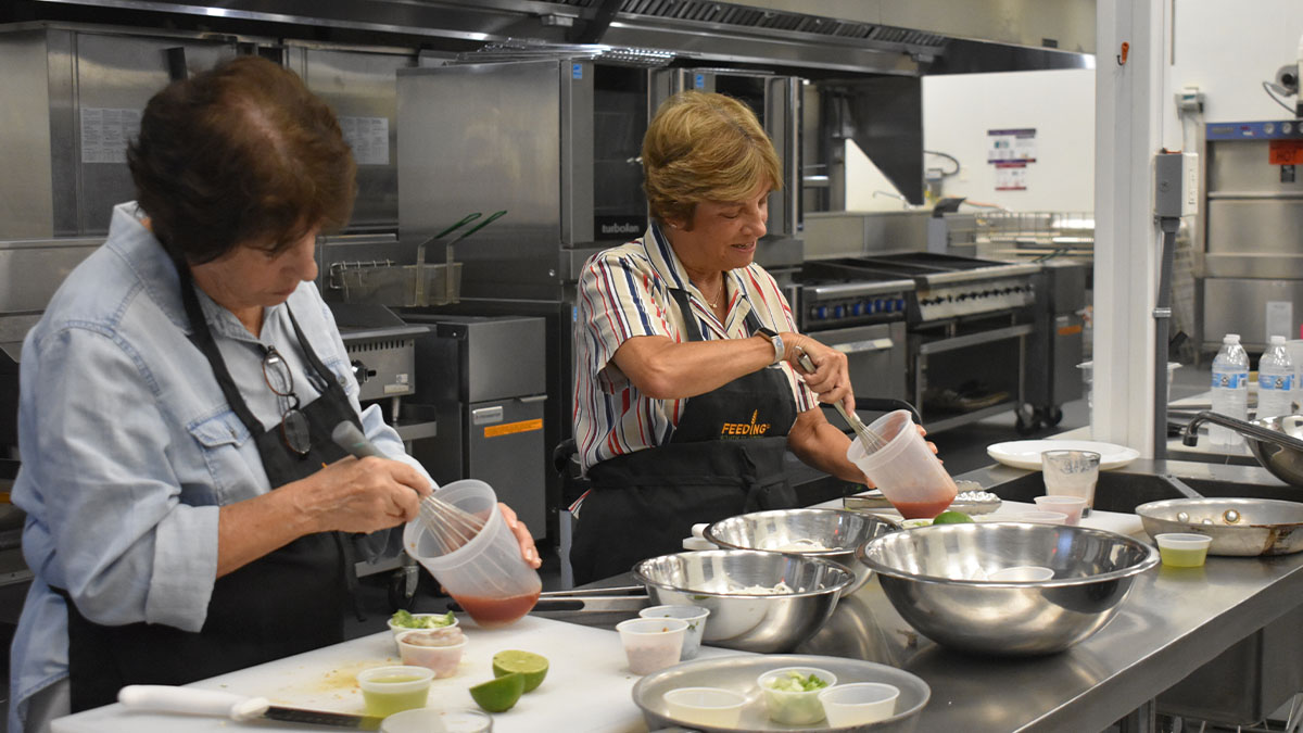Women stirring together sauces.