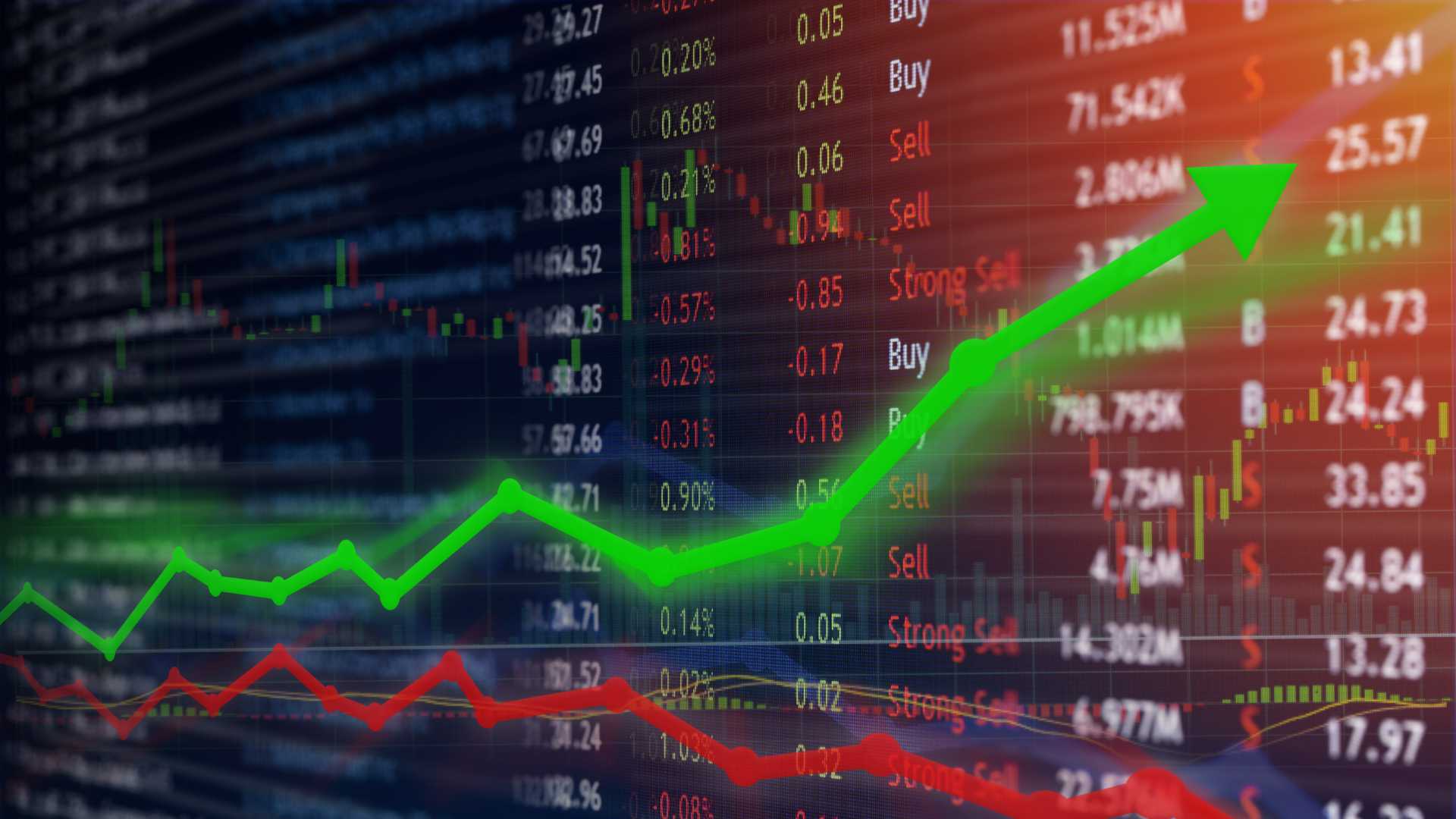 Image of a stock exchange out of focus with a list of different companies on it with a green upwards pointing arrow and a red downwards pointing arrow on top.